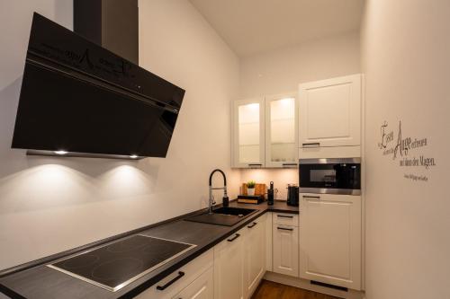 a kitchen with white cabinets and a sink and a microwave at Goethe Palais Suite Charlotte 4P l Lift I ParkplatzI Zentrum I Helios in Aue