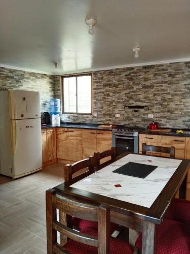 a kitchen with a table and a white refrigerator at S&J Casa Cabaña in El Tabo