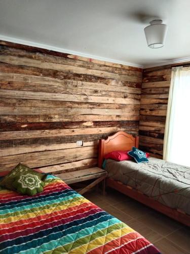 1 Schlafzimmer mit 2 Betten und einer Holzwand in der Unterkunft S&J Casa Cabaña in El Tabo