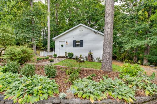 a garden with a small white house with a tree at Idyllic Cave Spring Studio with Patio and Fire Pit! in Cave Spring