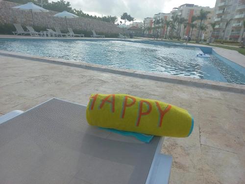 una balsa amarilla con la felicidad escrita en ella sentada junto a una piscina en Pool Breeze 202, en Punta Cana