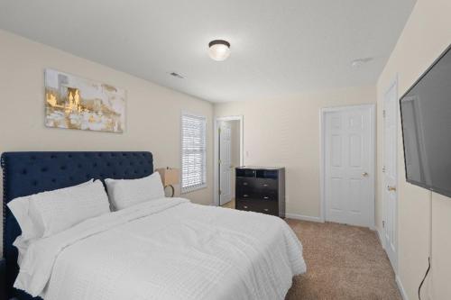a bedroom with a white bed and a flat screen tv at Exquisite E Charlotte house in Charlotte