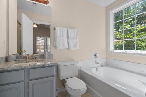a white bathroom with a tub and a toilet and a sink at Exquisite E Charlotte house in Charlotte