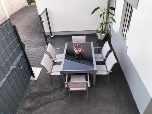 a table with chairs and a potted plant on a balcony at Gîte le Séquoia in Sélestat