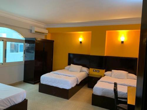 Red sea Hotel Marsa Alam في مرسى علم: سريرين في غرفة الفندق بجدران صفراء