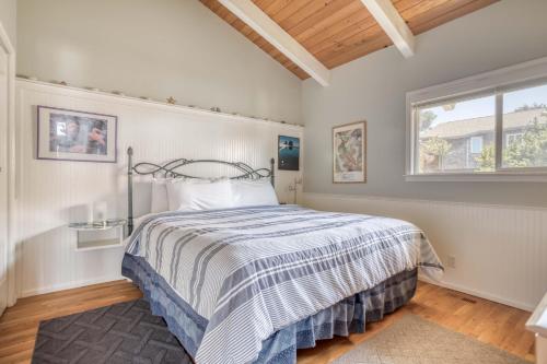 a bedroom with a bed with a striped comforter and a window at Captains Quarters in Lincoln City