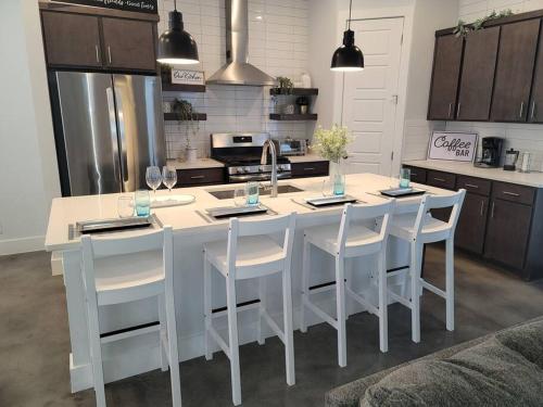 a kitchen with a white kitchen island with white chairs at The Alamo Riverwalk Pearl Modern 4 Bedroom Home in San Antonio