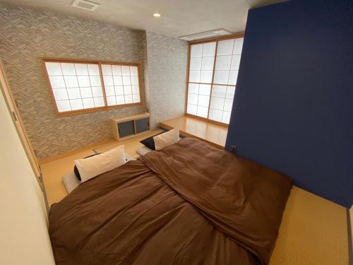 a bedroom with a large bed in a room with windows at 日月庵 BnB Sunmoon in Kanazawa