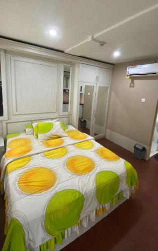 Elle comprend un grand lit avec des oreillers jaunes et verts. dans l'établissement 4BR cijerah small enchanted, à Bandung