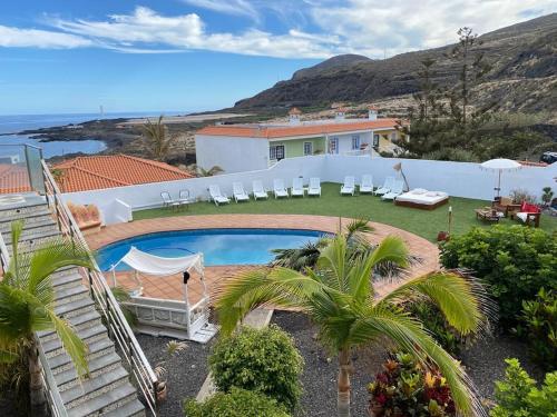 a house with a swimming pool and chairs and the ocean at Estrella de Sal in Villa de Mazo