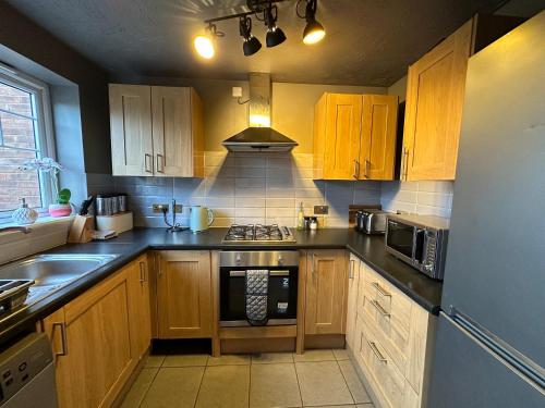 a kitchen with wooden cabinets and a stove top oven at Orchard House - Great Design, Comfortable furnitures, Free Wifi & Free Parking, Nice tidy Garden in Swindon