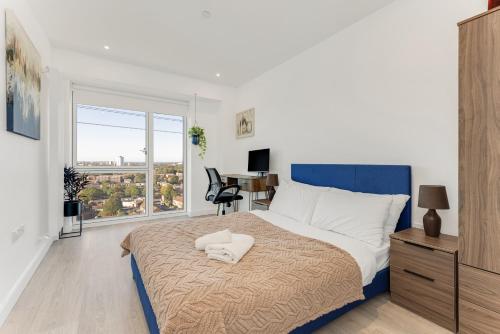 a bedroom with a bed and a desk and a window at Docklands Two Bed Apartment in London