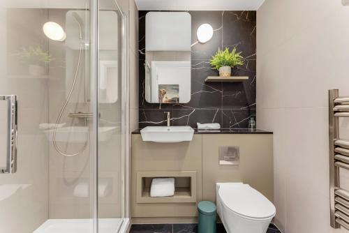 a bathroom with a shower and a toilet and a sink at Docklands Two Bed Apartment in London