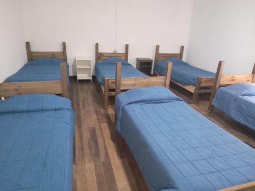 um grupo de quatro camas num quarto em Hostal 4 Estaciones em Los Andes