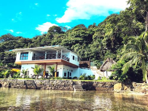 a house on the water in front of a mountain at Kasakai Beachouse in Juan Gallego