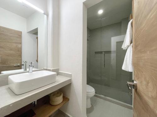y baño blanco con lavabo y ducha. en Rooms Huatulco en Santa Cruz - Huatulco