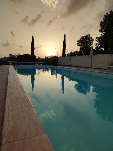 a swimming pool with the sunset in the background at Agriturismo Il Poggio Rosso di Maremma in Manciano