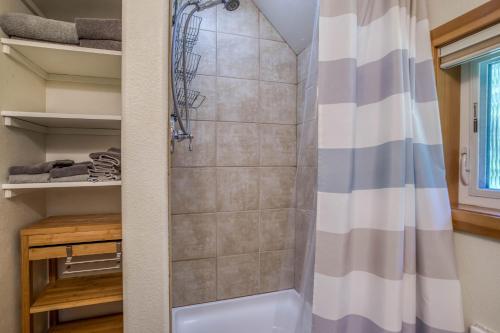 a walk in shower in a bathroom with a shower curtain at Guinevere's Cottage in Yachats