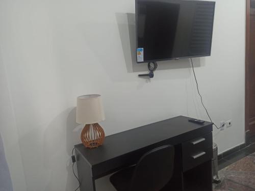 einen Schreibtisch mit einem TV, einer Lampe und einem Stuhl in der Unterkunft Ótimo Apto Centro SP Tudo a Pé in São Paulo