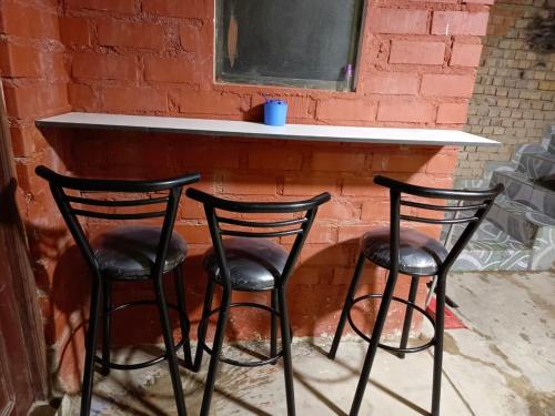 three black bar stools in front of a brick wall at Backpacker Oruro in Oruro
