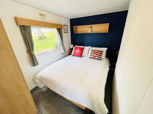 a small bedroom with a bed and a window at 3 Bedroom Caravan RW75, Thorness Bay, Dog Friendly, WiFi in Porchfield