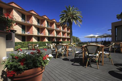 a patio at a hotel with chairs and tables and flowers at Hotel Desiree in Procchio