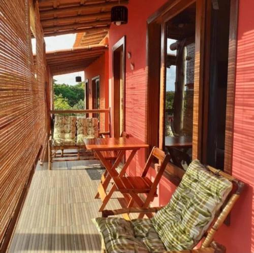 a porch with a table and chairs on a house at Natal Chalés Nova Caraiva in Caraíva