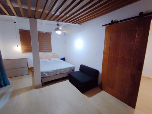a bedroom with a bed and a chair and a door at Kasakai Beachouse in Juan Gallego