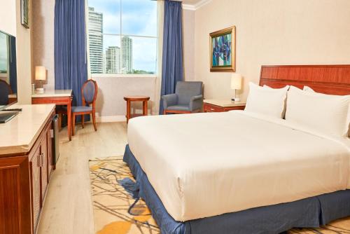 パナマシティにあるWaymore Hotel Spa & Casinoの大きなベッドとデスクが備わるホテルルームです。