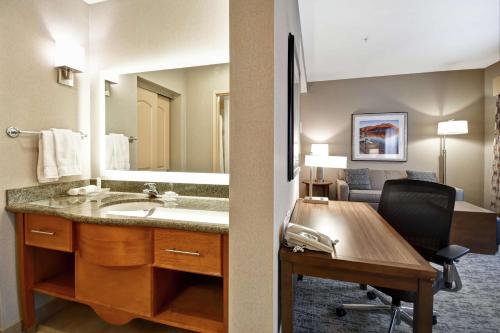 a bathroom with a sink and a desk with a chair at Homewood Suites by Hilton Boise in Boise