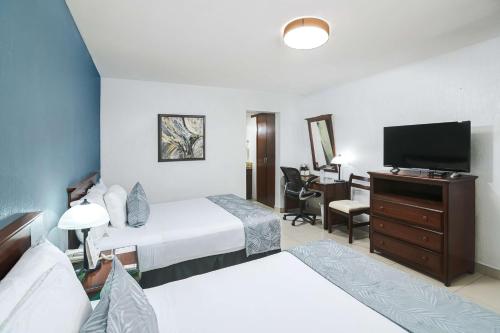 a hotel room with two beds and a flat screen tv at Best Western Plus San Jorge in Ciudad Obregón