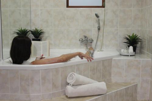 eine Person in einer Badewanne, die ein Buch liest in der Unterkunft Royal Guest House in Port Alfred