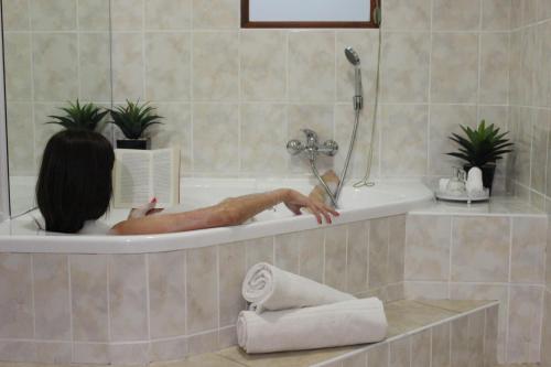 a person in a bath tub reading a book at Royal Guest House in Port Alfred