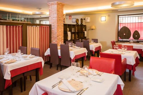 um restaurante com mesas brancas e cadeiras vermelhas em Hotel Villa de Cretas em Cretas