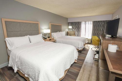 a hotel room with two beds and a flat screen tv at Hampton Inn Jacksonville - East Regency Square in Jacksonville