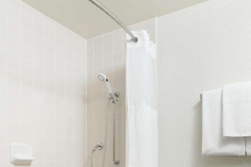 y baño con ducha con cortina blanca. en Hilton Boca Raton Suites, en Boca Raton