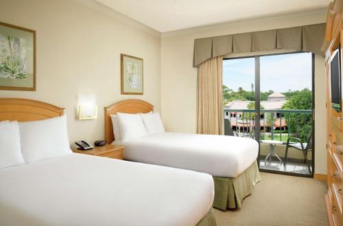 two beds in a hotel room with a balcony at Hilton Boca Raton Suites in Boca Raton