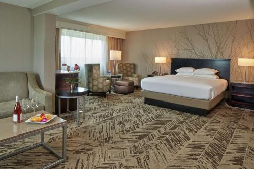a hotel room with a bed and a living room at Hilton Cincinnati Airport in Florence