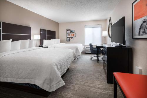 a hotel room with two beds and a desk at Hampton Inn Loveland in Loveland