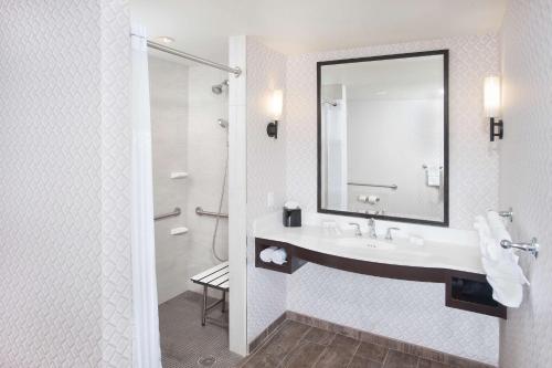 a bathroom with a sink and a mirror and a shower at Hilton Garden Inn Burbank Los Angeles in Burbank