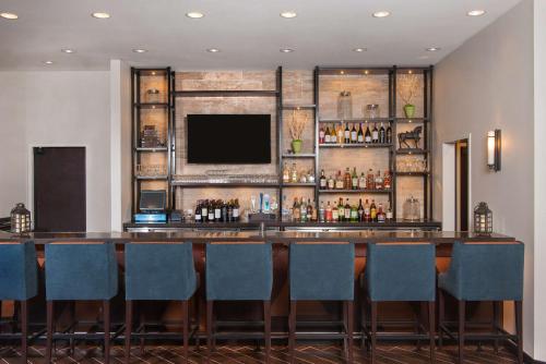 a bar in a hotel with blue chairs and a television at Hilton Garden Inn Burbank Los Angeles in Burbank