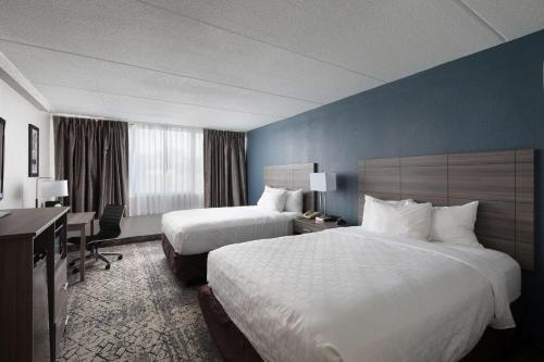 a hotel room with two beds and a desk at Clarion Hotel & Convention Center Joliet in Joliet