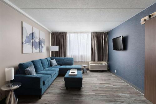 a living room with a blue couch and a tv at Clarion Hotel & Convention Center Joliet in Joliet