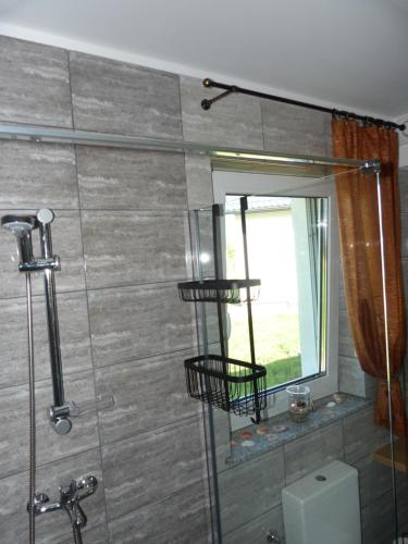 łazienka z prysznicem, toaletą i oknem w obiekcie Sosnówka - domki nad morzem w mieście Kopalino