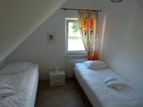 2 łóżka pojedyncze w pokoju z oknem w obiekcie Sosnówka - domki nad morzem w mieście Kopalino