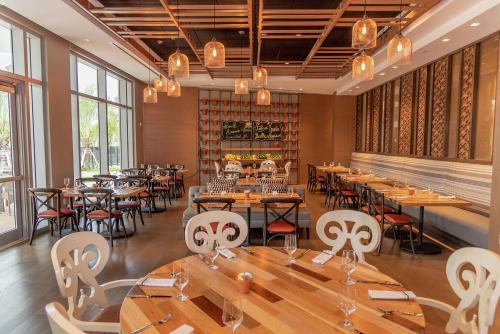 a restaurant with wooden tables and chairs and windows at Hilton Miami Dadeland in South Miami