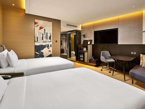 a hotel room with two beds and a flat screen tv at Swissotel The Stamford in Singapore