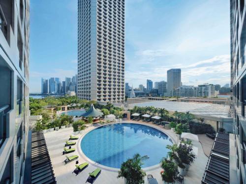 einen Blick über einen Pool mit einem hohen Gebäude in der Unterkunft Swissotel The Stamford in Singapur