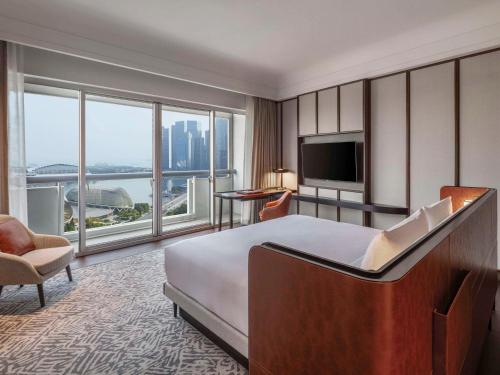 a hotel room with a bed and a large window at Fairmont Singapore in Singapore