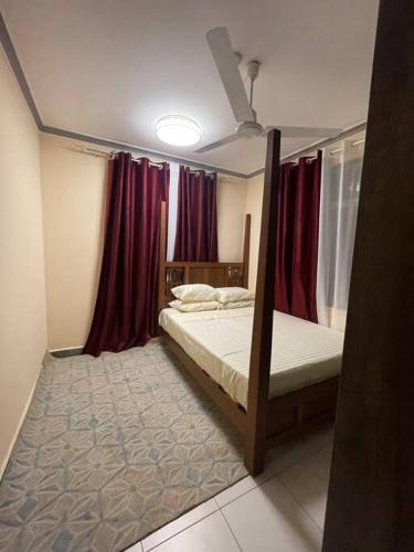 - une chambre avec 2 lits superposés et des rideaux rouges dans l'établissement The Tropics Apartment Mombasa, à Mombasa